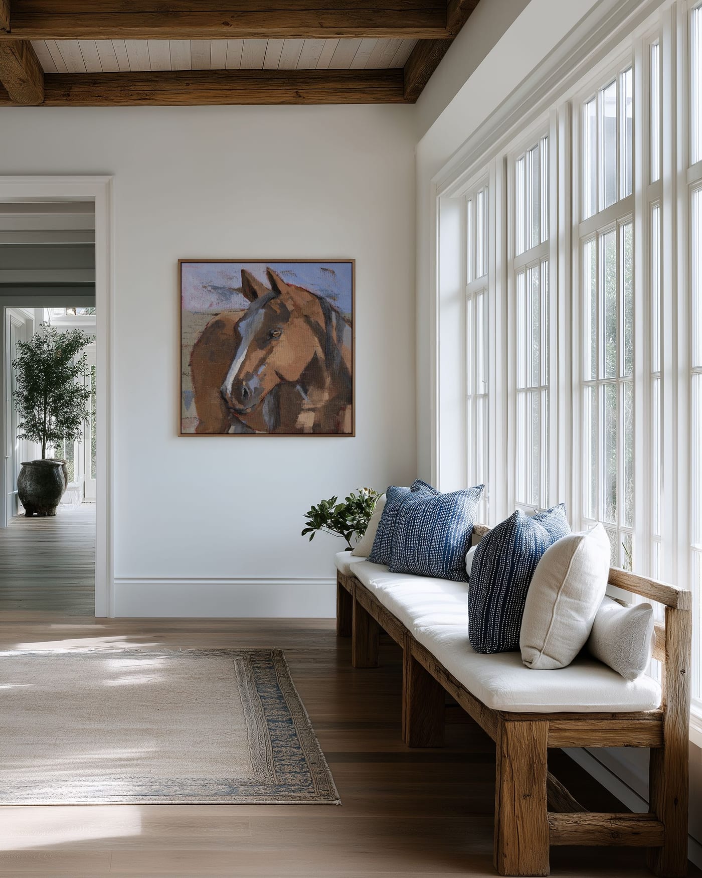 Horse portrait painting in a light-filled entryway beside a wooden bench